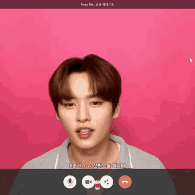 a young man is talking on a video call with a pink background ..