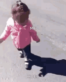 a little girl in a pink jacket is running down the street with her shadow on the ground .
