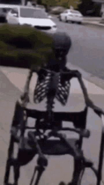 a skeleton is sitting in a wheelchair on a sidewalk .