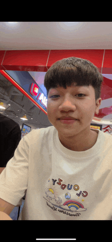 a young man wearing a white t-shirt with a rainbow on the front