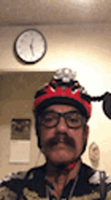 a man with a mustache wearing a helmet and glasses is taking a selfie .