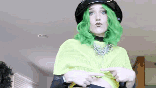 a woman with green hair is wearing a black hat and a neon green top