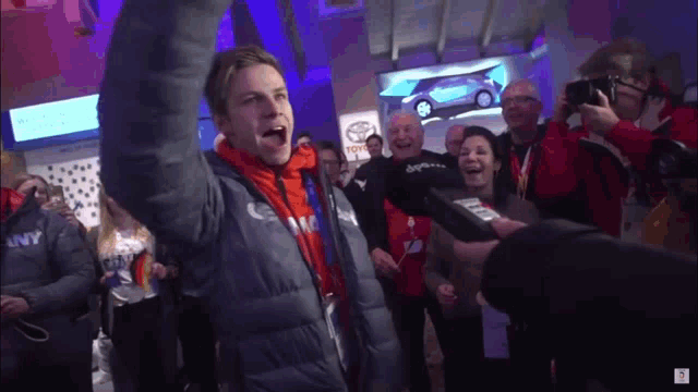 a man wearing a jacket that says city on it stands in front of a crowd