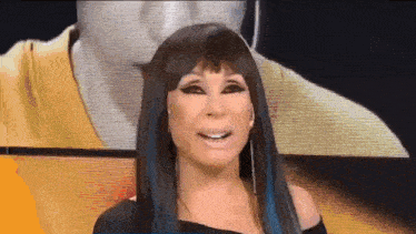 a woman with long black hair and blue streaks is smiling in front of a man 's face