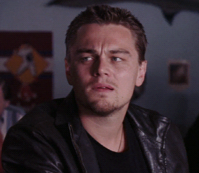 a man wearing a black shirt and a leather jacket looks at the camera