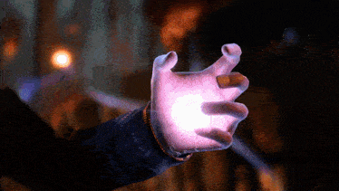 a person 's hand is reaching out towards a light
