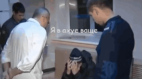 a man in a white shirt is talking to a man in a black hat while another man in a blue uniform looks on