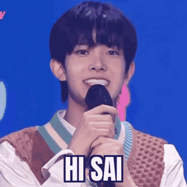 a young man is smiling while holding a microphone and saying hi sai .
