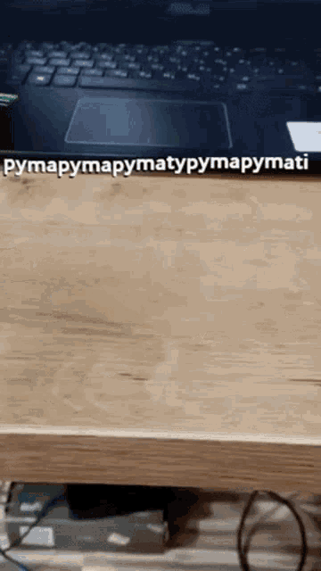 a laptop is sitting on a wooden desk with the words pymapymapymapymati written on it