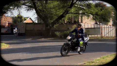 a man is riding a motorcycle down a street with a sign that says ' a ' on it