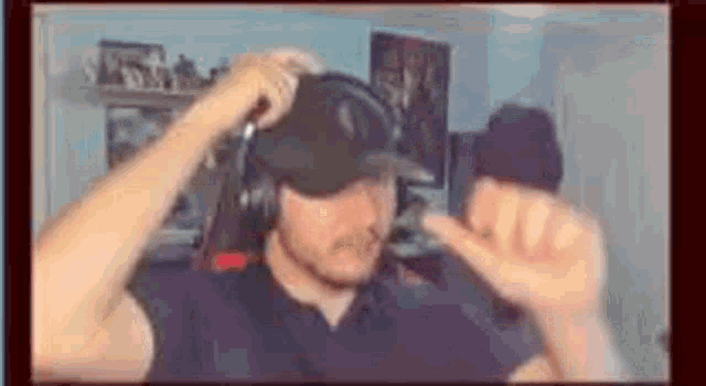 a man wearing headphones and a baseball cap is making a hand gesture .