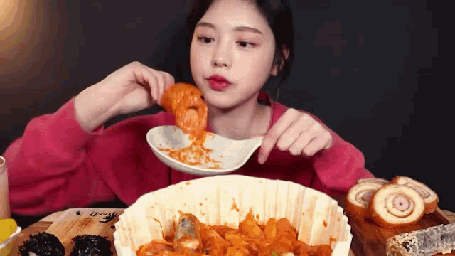 a woman is sitting at a table eating food from a bowl and spoon .