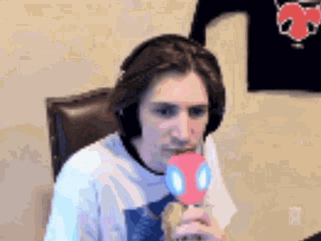 a man wearing headphones is holding a pink spider man toy in his mouth