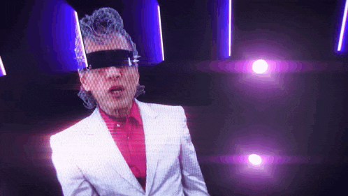a man wearing a white suit and sunglasses is standing in front of a purple light
