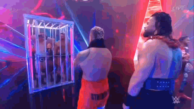 a group of men are standing in front of a cage .