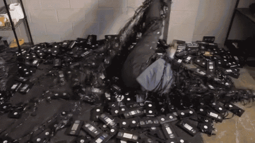a person is laying on the floor surrounded by a pile of vhs tapes
