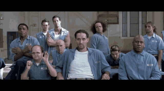 a group of men in prison uniforms with one man wearing a name tag that says ' smith '