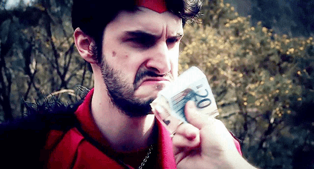 a man in a red shirt is holding a stack of 20 euro bills