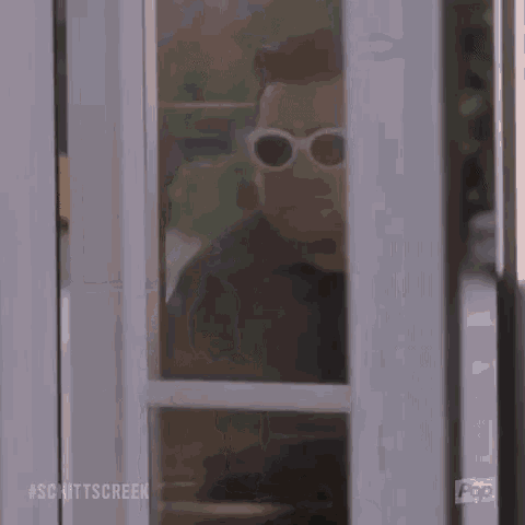 a man wearing sunglasses is standing in a doorway .