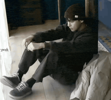 a man is sitting on the floor tying his shoes