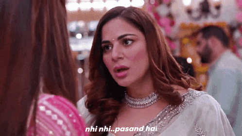 a woman in a white saree is talking to another woman in a pink shirt .