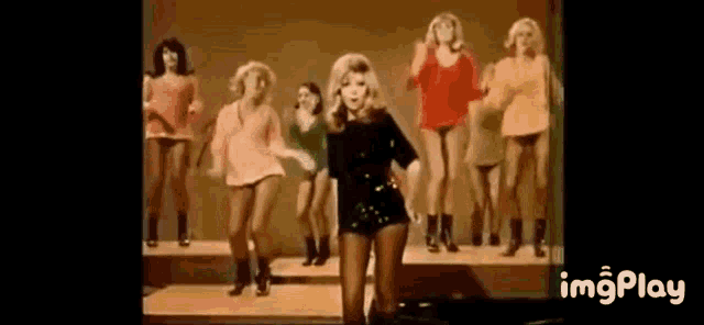 a woman is standing in front of a group of women dancing .