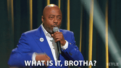 a man in a blue suit is holding a microphone and saying what is it brotha