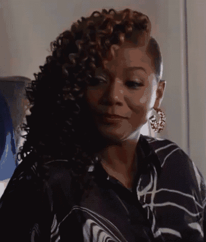 a woman with curly hair is sitting on a plane wearing earrings and a striped shirt .