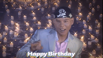 a man is standing in front of a wall of candles and says happy birthday