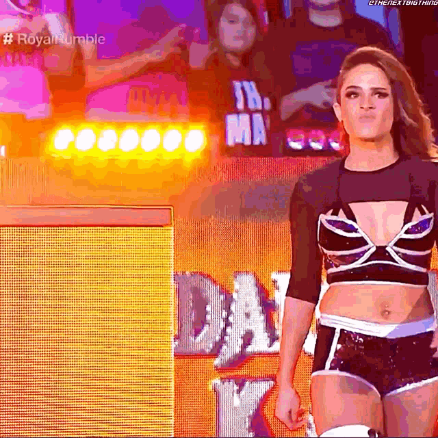 a woman in a crop top and shorts stands in front of a sign that says ' the next thing '