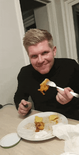 a man is sitting at a table eating a piece of food with a fork