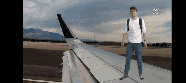 a man standing on the wing of an airplane with the word noe on the bottom right