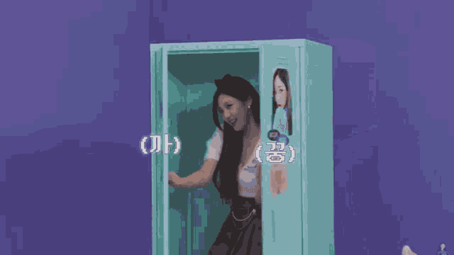 a woman is standing in front of a blue cabinet and waving .