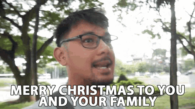 a man says merry christmas to you and your family in front of trees