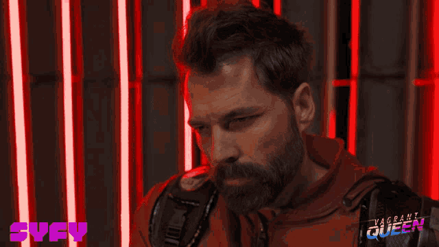 a man with a beard is standing in front of a sign that says svcy on it