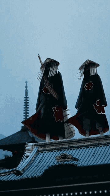 a couple of people standing on top of a building with a cloud symbol on their outfits