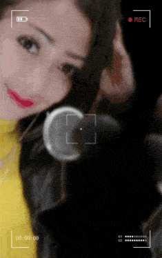 a woman in a yellow shirt is being recorded with a rec button on the bottom right