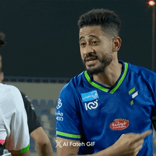 a man wearing a blue and green soccer jersey with the number 100 on it