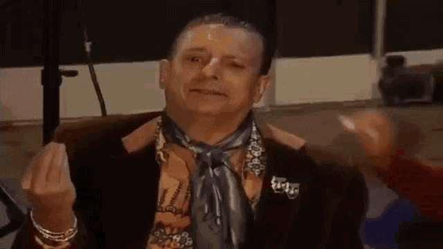 a man in a suit and tie is sitting in a chair making a funny face .