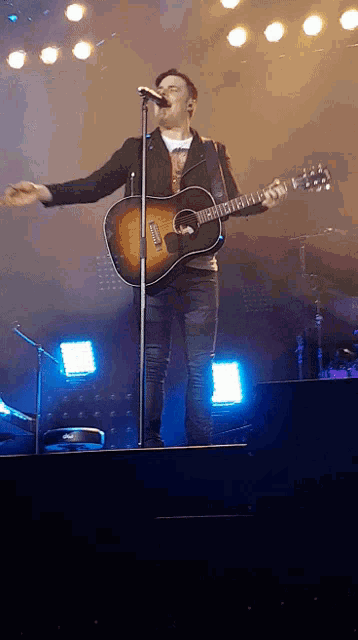 a man is singing into a microphone while holding a guitar