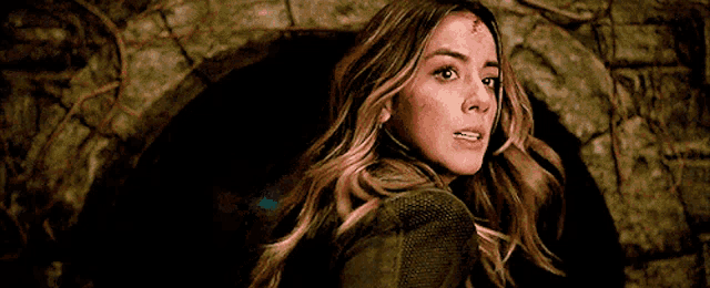 a woman with blood on her face is standing in a dark room looking at the camera .