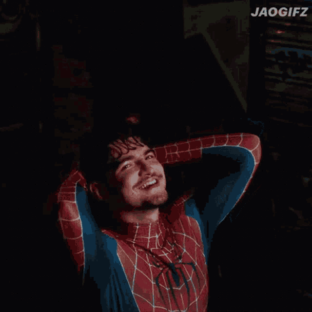 a man in a spider man costume is smiling with his hands behind his head ..