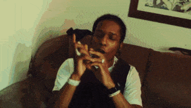 a young man is sitting on a couch smoking a cigarette