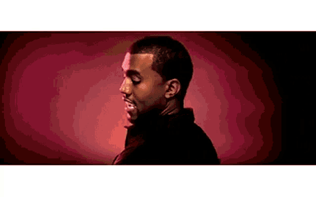 a man in a black jacket is standing in front of a red background and smiling .