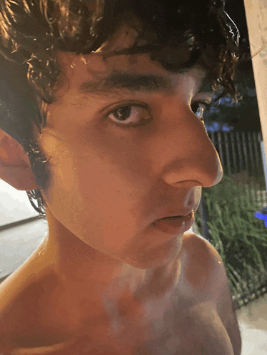 a close up of a young man 's face with water on his hair
