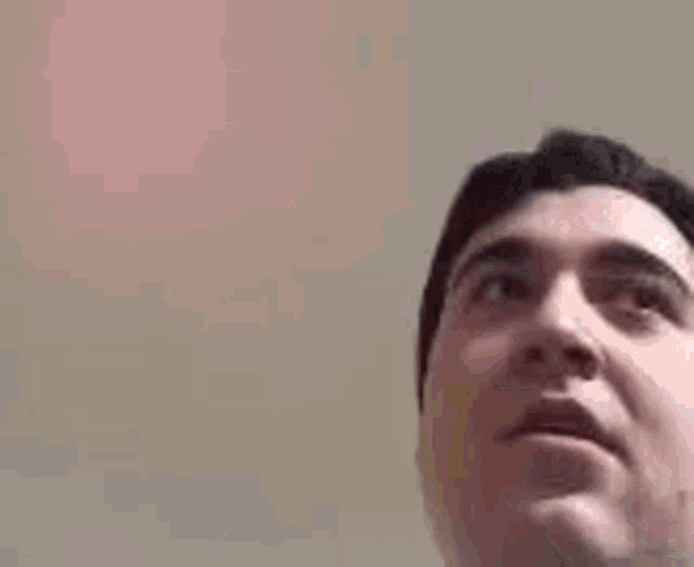 a man is holding a yellow balloon and looking up at the camera .