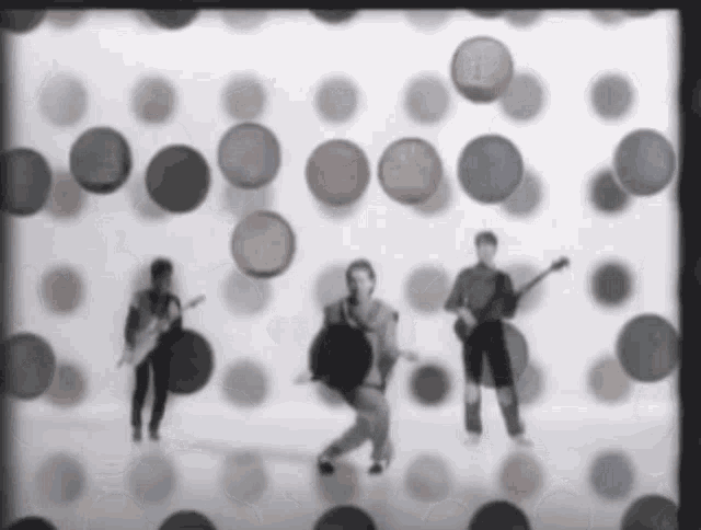 a group of people playing instruments in front of a polka dot wall