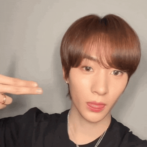 a close up of a person making a peace sign with their tongue out
