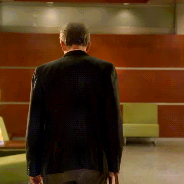 a man in a black jacket is walking in a room