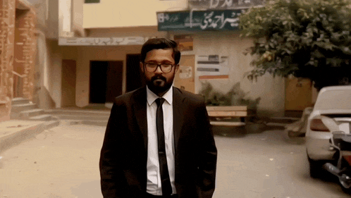 a man in a suit and tie stands in front of a building that has a sign that says ' a ' on it